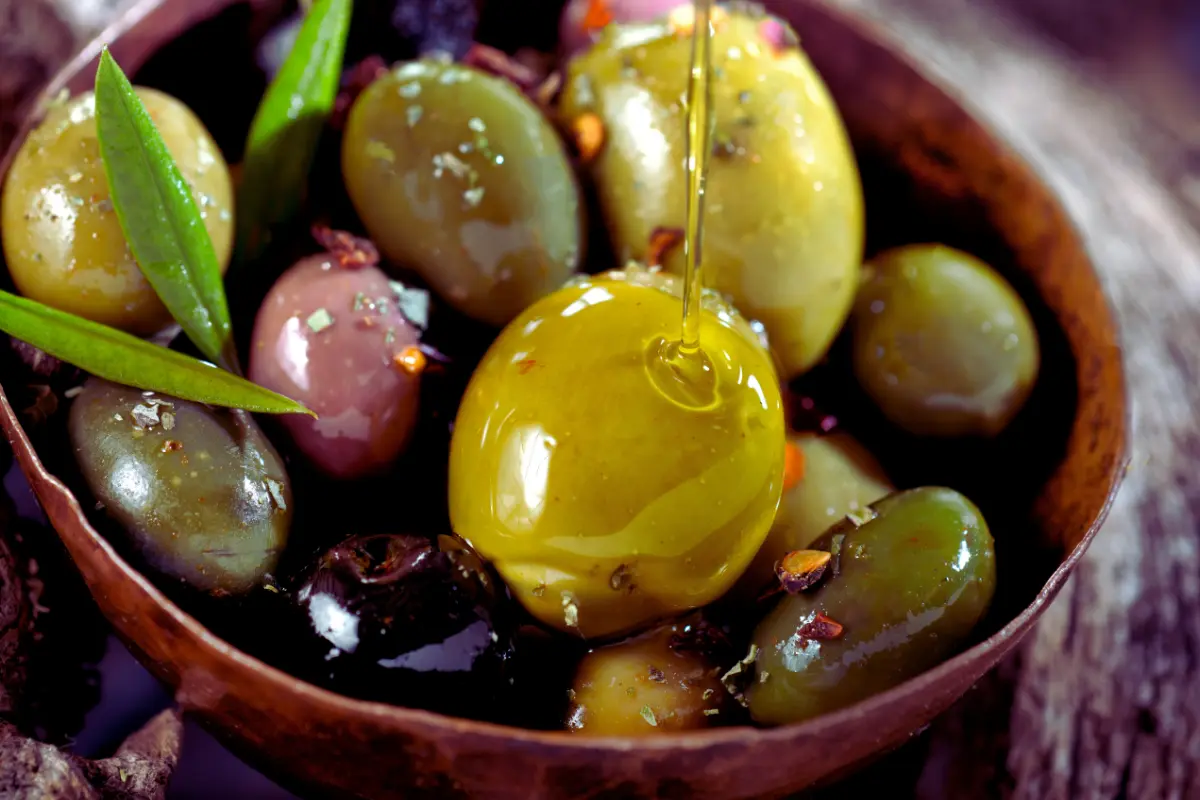 A variety of olives displayed in a rustic bowl, emphasizing their diverse colors and textures, ideal for Mediterranean dishes.